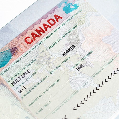 Close-up of a Canadian work visa document with "CANADA" in red letters, showing a multiple-entry worker visa with bilingual labels and security patterns.